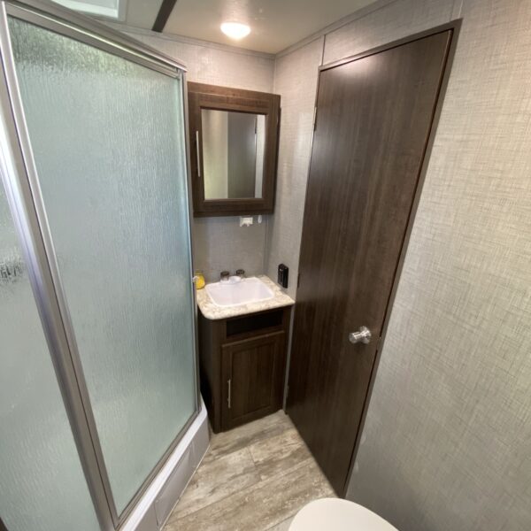 The front restroom features a stand up shower, porcelain toilet and a sink.